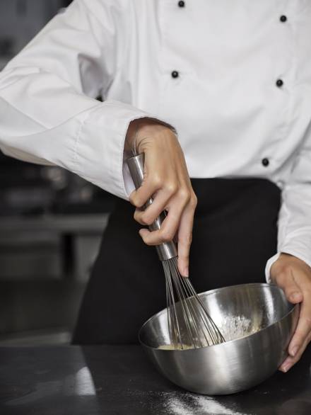 female-chef-kitchen-beating-eggs-with-whisk-min